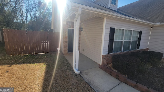 view of property exterior featuring brick siding, fence, and a lawn