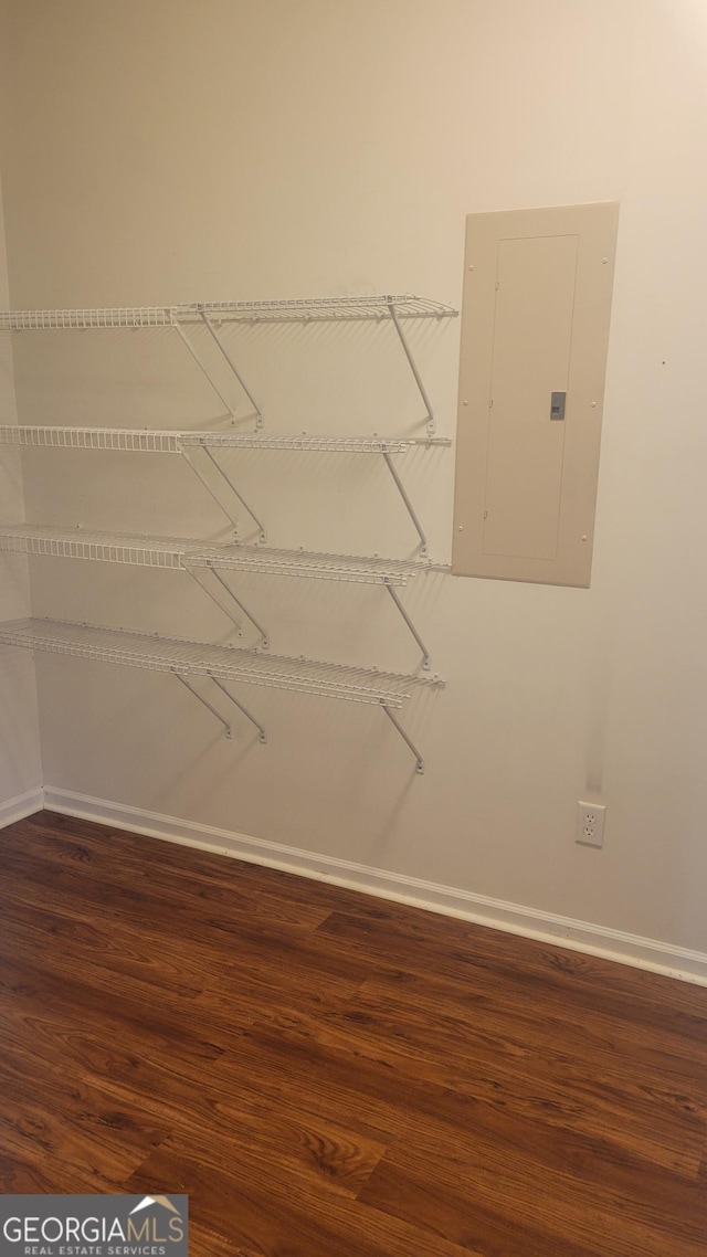 walk in closet with electric panel and wood finished floors