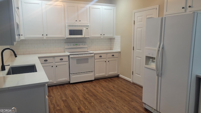 kitchen featuring white appliances, white cabinets, decorative backsplash, dark wood-style floors, and a sink