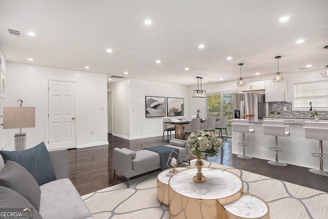 living area with recessed lighting, wood finished floors, visible vents, and baseboards