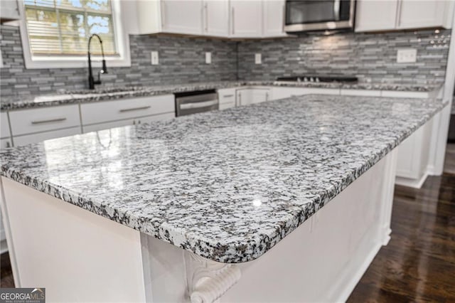 kitchen with light stone counters, backsplash, appliances with stainless steel finishes, and white cabinets