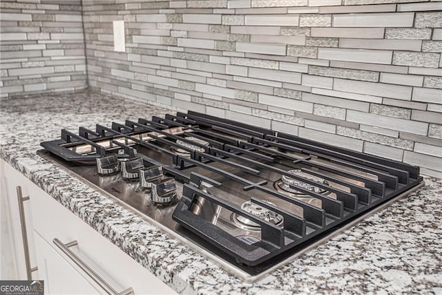 interior details featuring backsplash and stainless steel gas stovetop