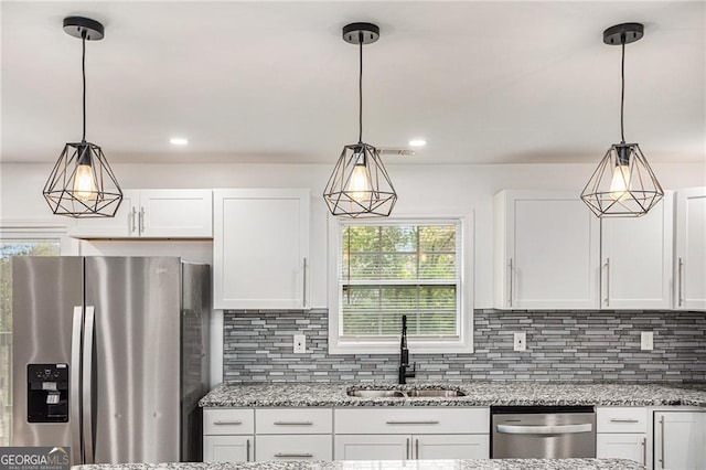 kitchen featuring light stone countertops, a sink, white cabinets, appliances with stainless steel finishes, and tasteful backsplash