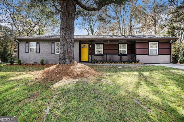 ranch-style home featuring brick siding, covered porch, and a front yard