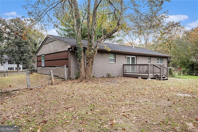 back of house with a gate, fence, a wooden deck, a yard, and brick siding