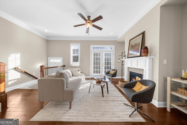 living area with hardwood / wood-style floors, baseboards, recessed lighting, a warm lit fireplace, and crown molding