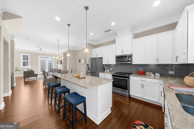 kitchen with dark wood-style floors, ornamental molding, stainless steel appliances, open floor plan, and tasteful backsplash