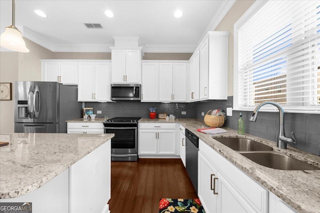 kitchen with ornamental molding, white cabinets, stainless steel appliances, and a sink