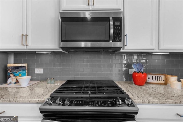 kitchen featuring decorative backsplash, white cabinets, and appliances with stainless steel finishes