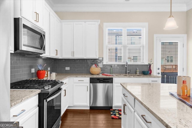 kitchen featuring ornamental molding, a sink, stainless steel appliances, white cabinets, and decorative backsplash