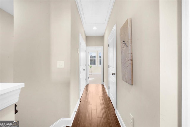 hall featuring baseboards, attic access, and wood finished floors