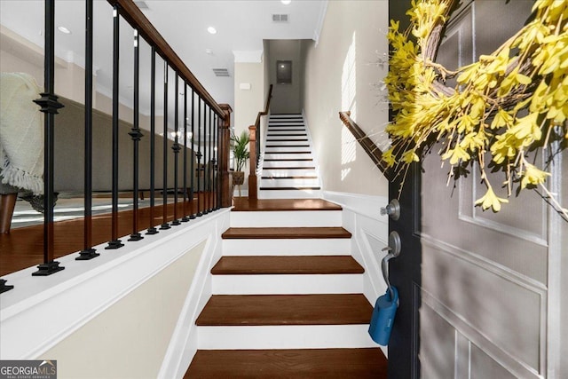 stairs with a wainscoted wall, a decorative wall, wood finished floors, and visible vents