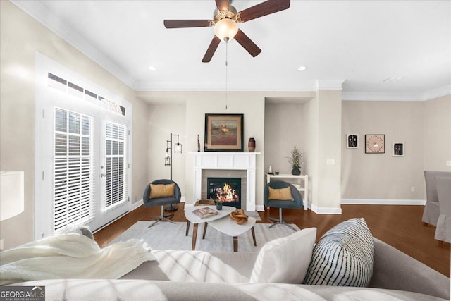 living room featuring baseboards, a lit fireplace, wood finished floors, and crown molding