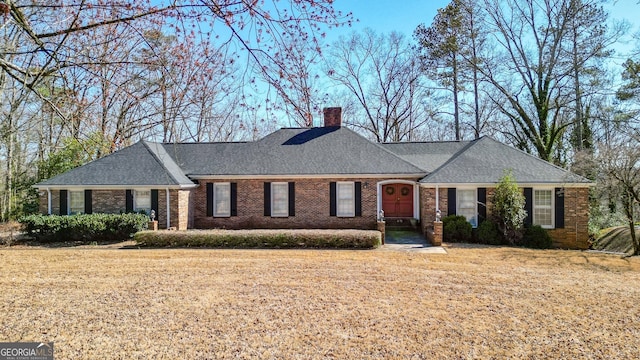 ranch-style home featuring brick siding, a chimney, and a front yard