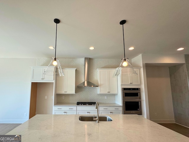 kitchen with decorative backsplash, wall chimney exhaust hood, black stovetop, double oven, and a sink