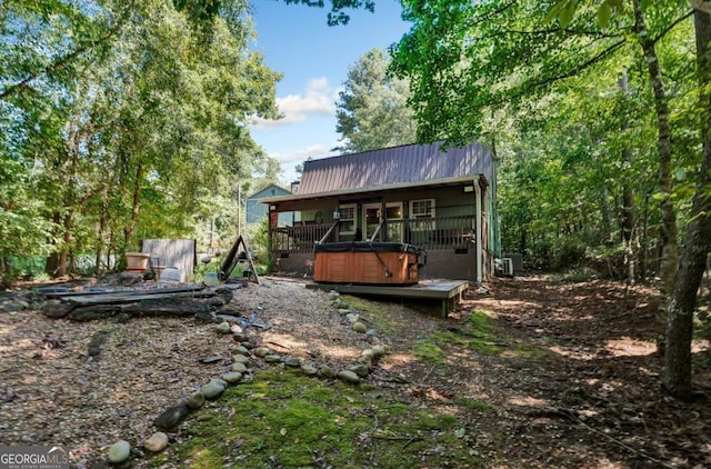 rear view of house with metal roof, a wooden deck, and a hot tub