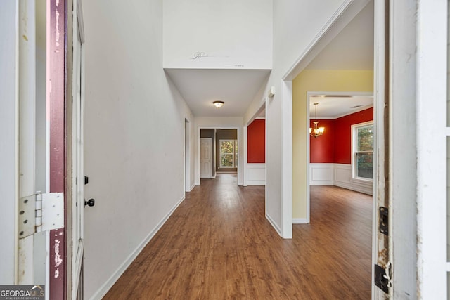 foyer with a wainscoted wall, a decorative wall, wood finished floors, and an inviting chandelier