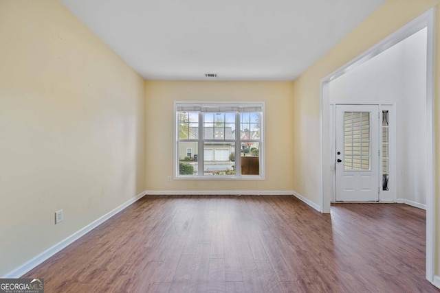 unfurnished room featuring visible vents, baseboards, and dark wood-type flooring