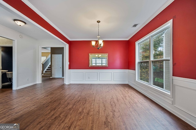 unfurnished dining area featuring visible vents, crown molding, an inviting chandelier, and wood finished floors