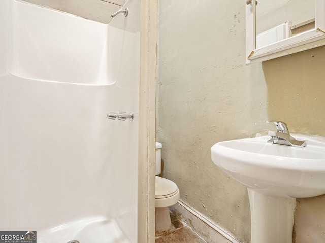 bathroom featuring a sink, a shower stall, and toilet