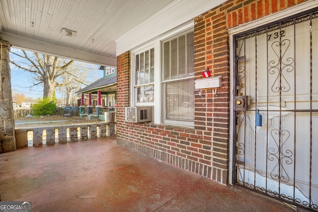 property entrance with covered porch, brick siding, and cooling unit