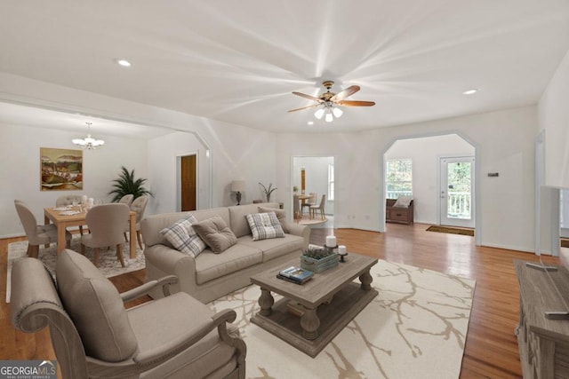 living area with recessed lighting, baseboards, arched walkways, wood finished floors, and ceiling fan with notable chandelier