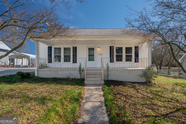 bungalow-style house featuring covered porch, fence, and a detached carport