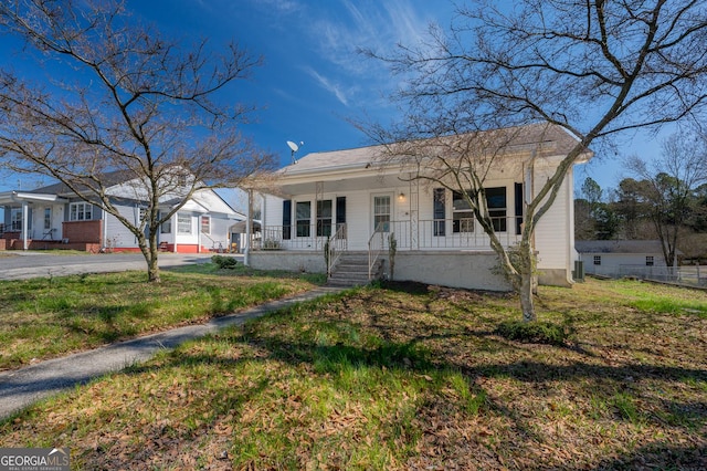 bungalow with covered porch, aphalt driveway, and a front yard