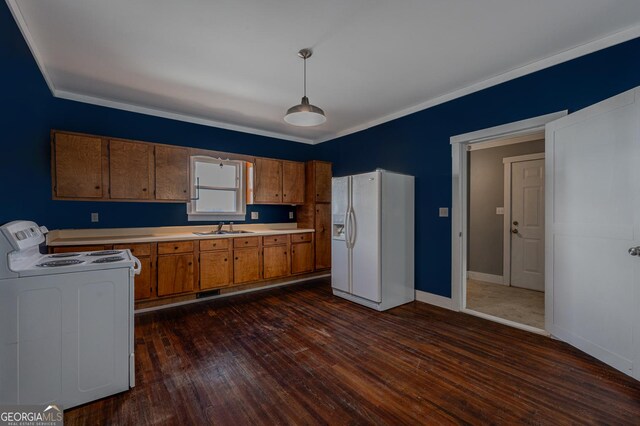 kitchen with dark wood-style flooring, brown cabinets, light countertops, a sink, and white appliances