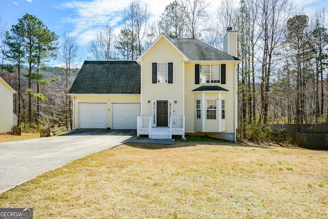 view of front of house with a front yard, roof with shingles, a chimney, driveway, and an attached garage