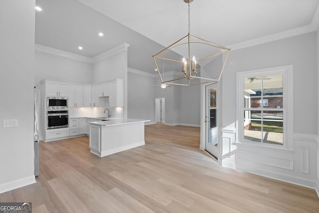 kitchen featuring a notable chandelier, stainless steel appliances, open floor plan, white cabinetry, and a sink