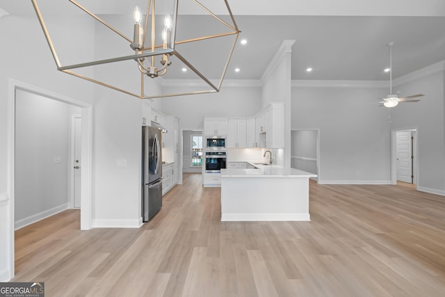 kitchen with stainless steel appliances, a sink, white cabinetry, open floor plan, and light countertops