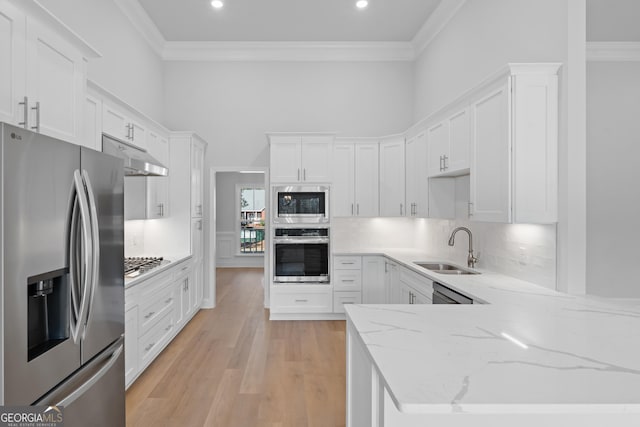 kitchen with appliances with stainless steel finishes, ornamental molding, a sink, light stone countertops, and backsplash