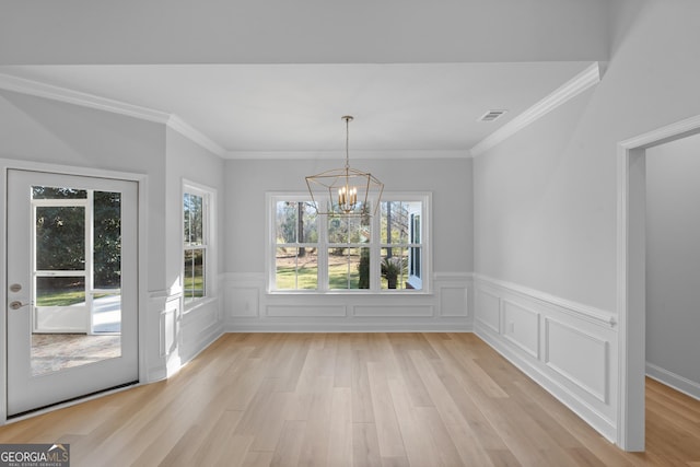 unfurnished dining area featuring a notable chandelier, visible vents, ornamental molding, wainscoting, and light wood finished floors