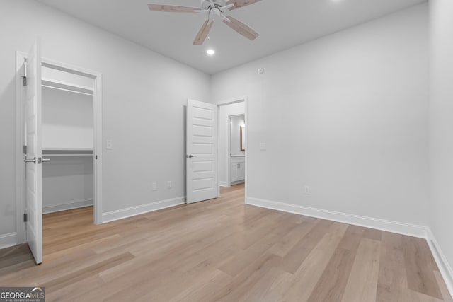 unfurnished bedroom featuring light wood-style flooring, baseboards, a walk in closet, and recessed lighting