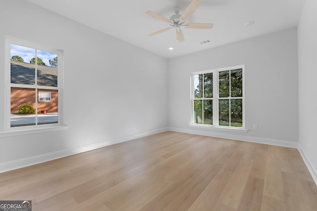 empty room with light wood-style floors, baseboards, visible vents, and a ceiling fan