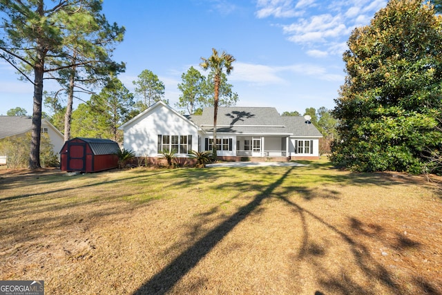 back of property featuring a storage shed, a yard, and an outdoor structure