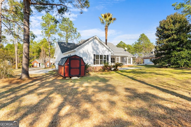 rear view of property with a yard, a shed, and an outbuilding