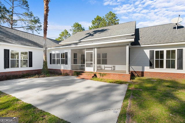 view of front of house featuring a shingled roof, a front yard, and a sunroom