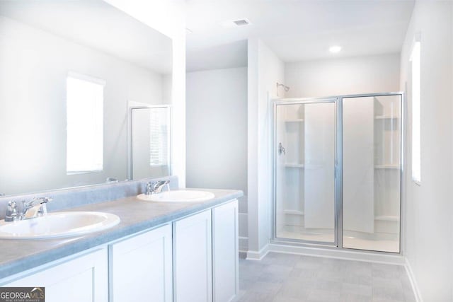 full bathroom with double vanity, a shower stall, visible vents, and a sink