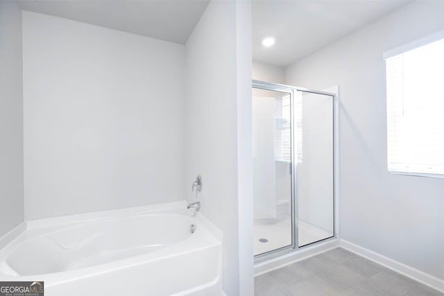 full bathroom with a garden tub, a shower stall, and baseboards