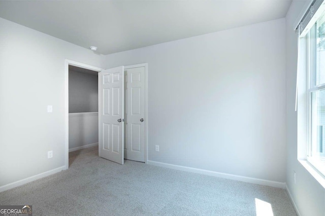 unfurnished bedroom featuring light carpet and baseboards