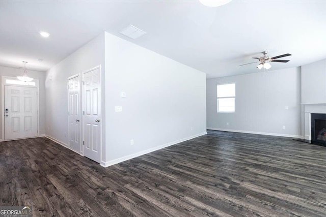 unfurnished living room with a fireplace, baseboards, and dark wood finished floors