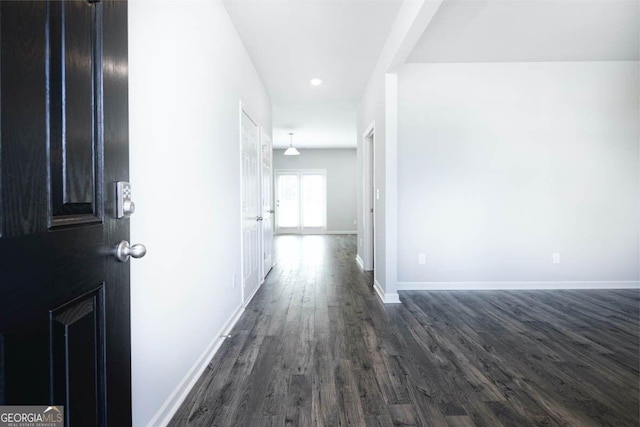 hall featuring dark wood-type flooring and baseboards