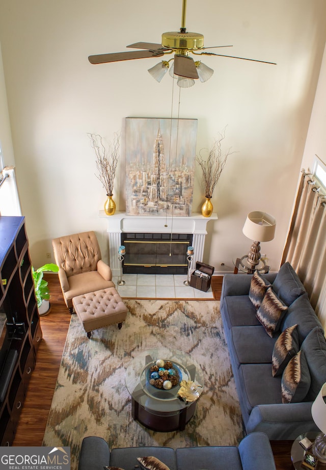 living room featuring a tiled fireplace, a ceiling fan, and wood finished floors