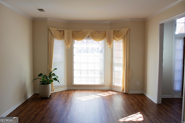 empty room with baseboards, visible vents, dark wood-type flooring, and ornamental molding