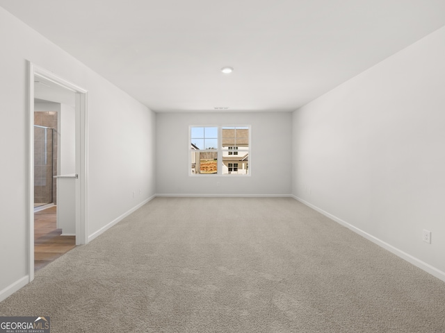 unfurnished room featuring light carpet and baseboards