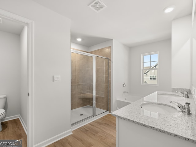 bathroom featuring a sink, a stall shower, wood finished floors, and toilet