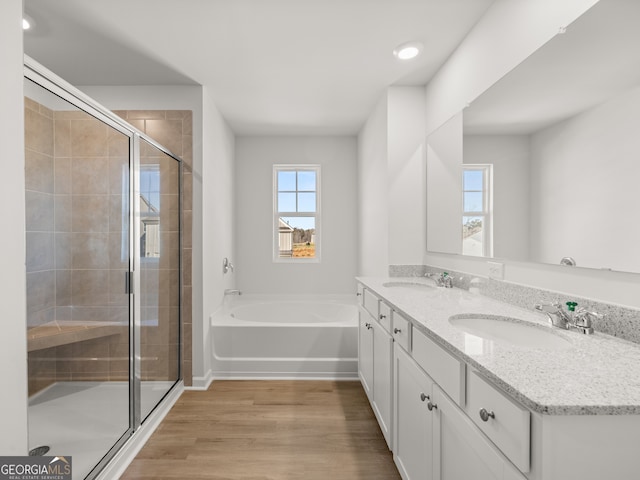 bathroom with wood finished floors, a sink, a bath, and a shower stall