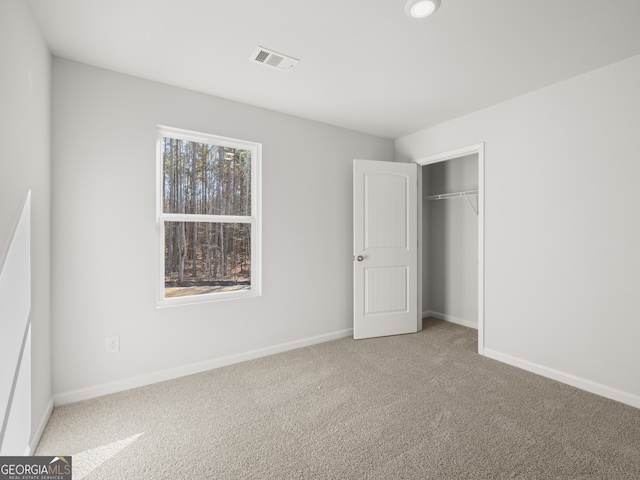 unfurnished bedroom with carpet floors, a closet, visible vents, and baseboards